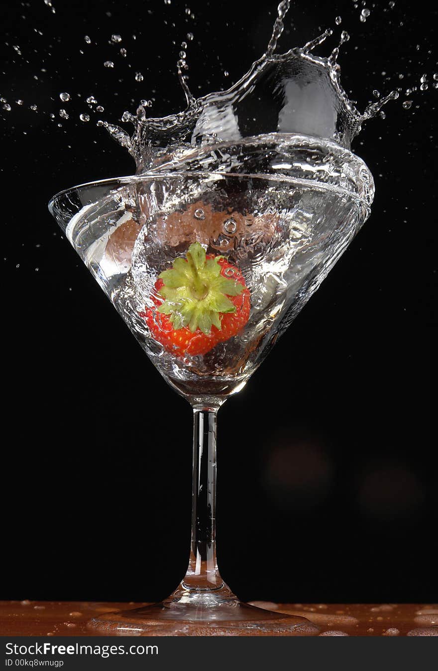 Falling strawberry in a glass with a drink