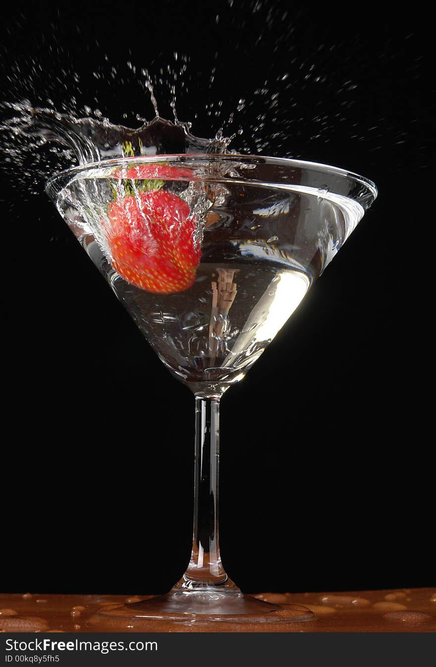 Falling strawberry in a glass with a drink