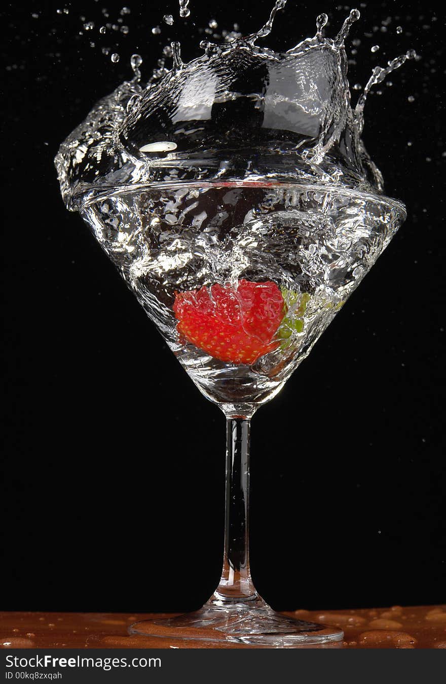 Falling strawberry in a glass with a drink