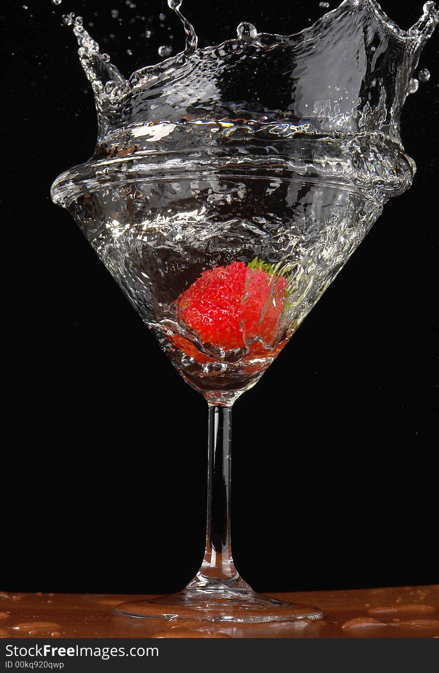 Falling strawberry in a glass with a drink