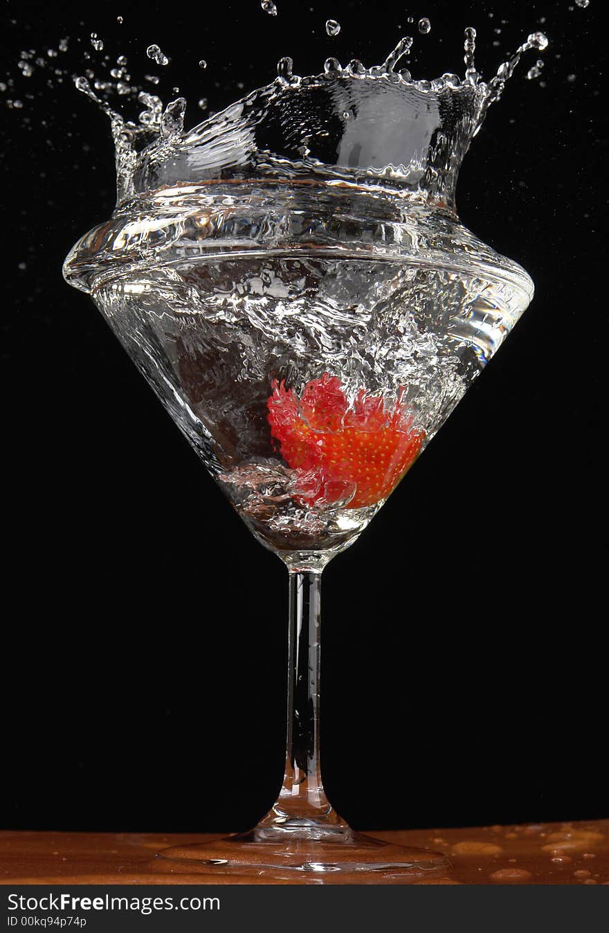 Falling strawberry in a glass with a drink