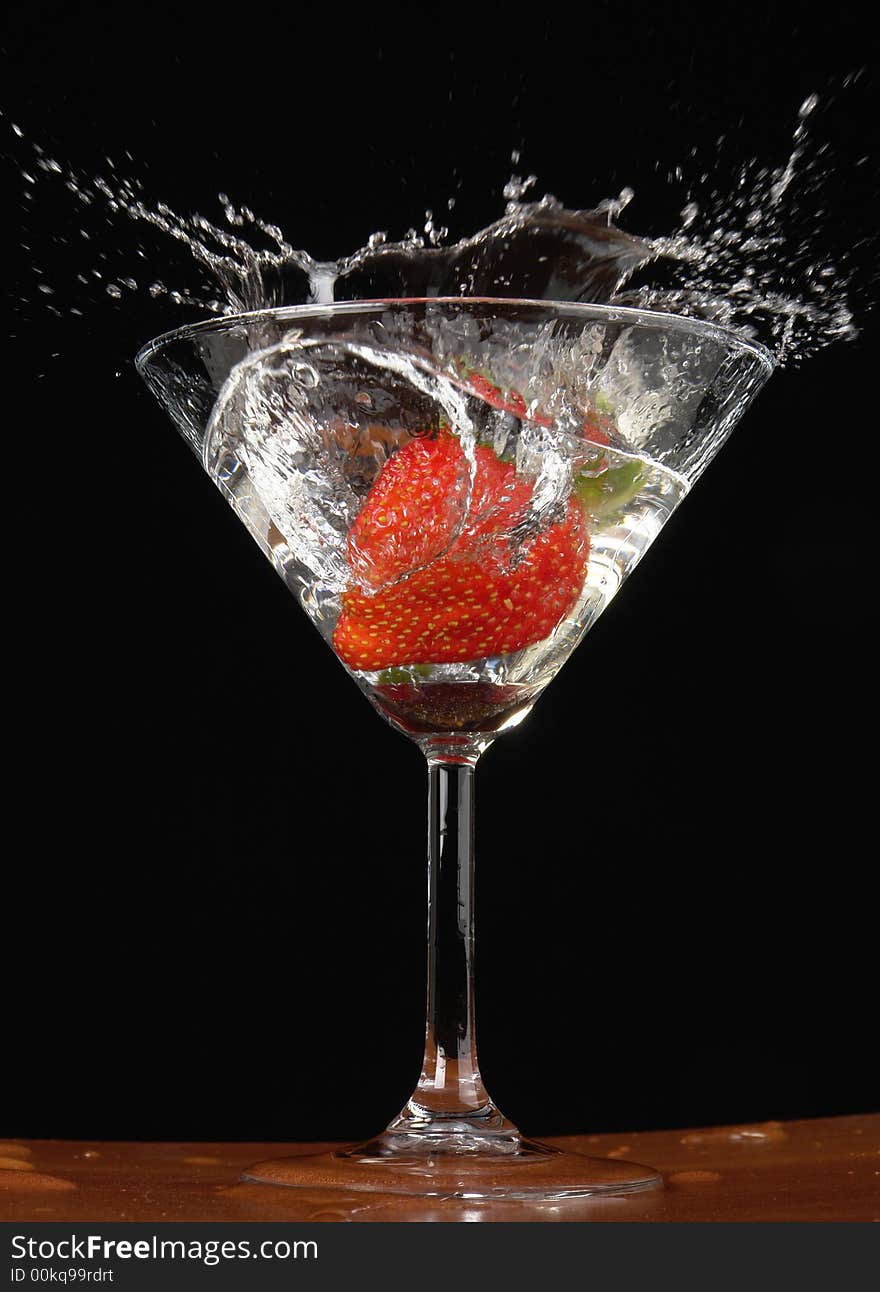 Falling strawberry in a glass with a drink