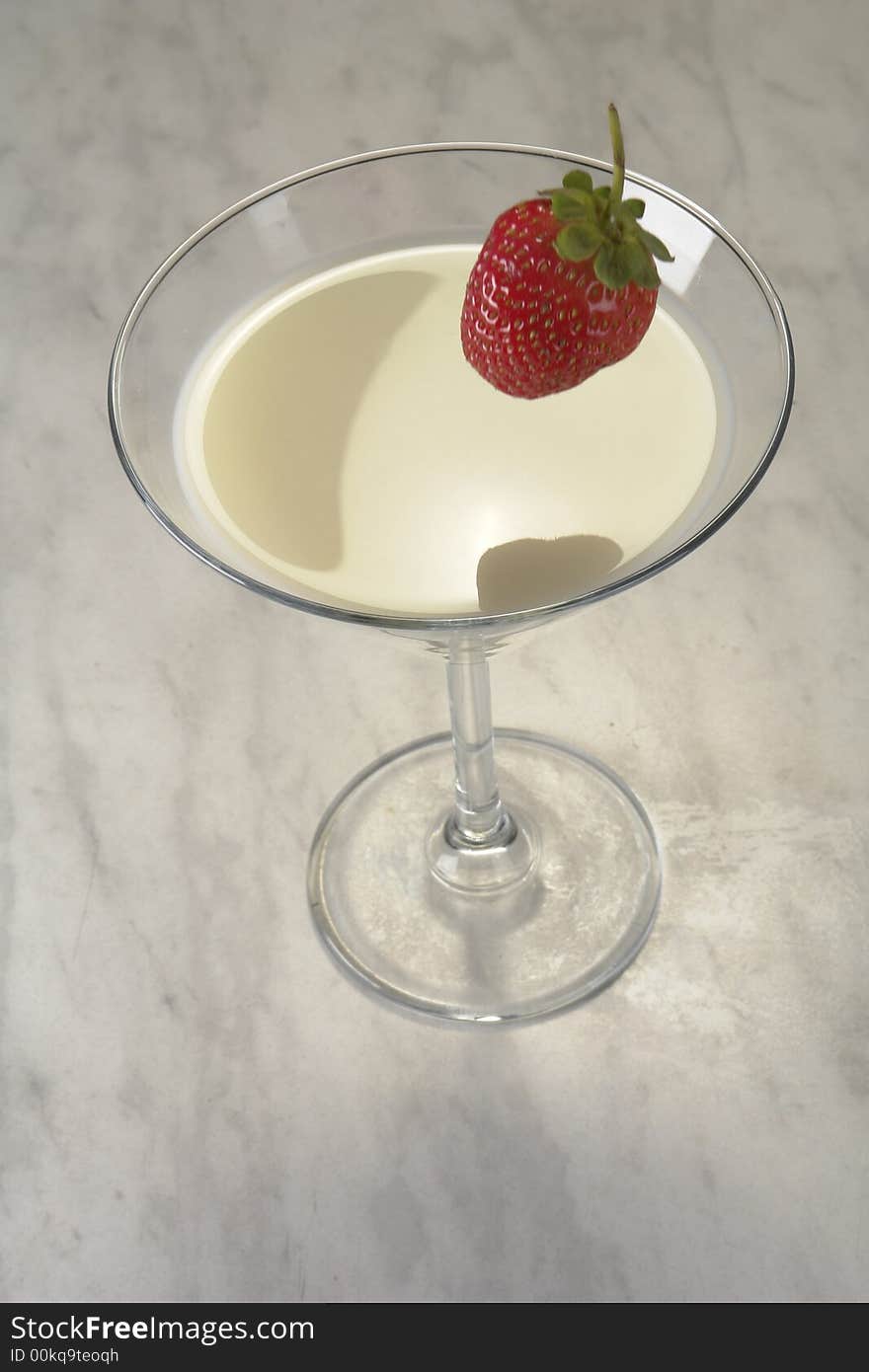 Falling strawberry in a glass with milk