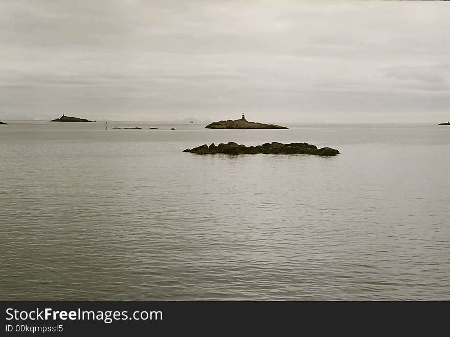 Sea and small islands in Norway. Gray cloudy sky.