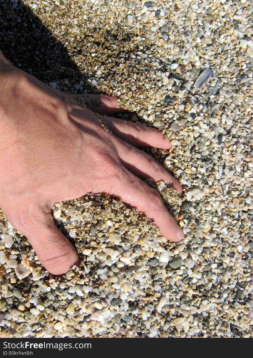 A close up of a female hand merged in the pebbles at the beach