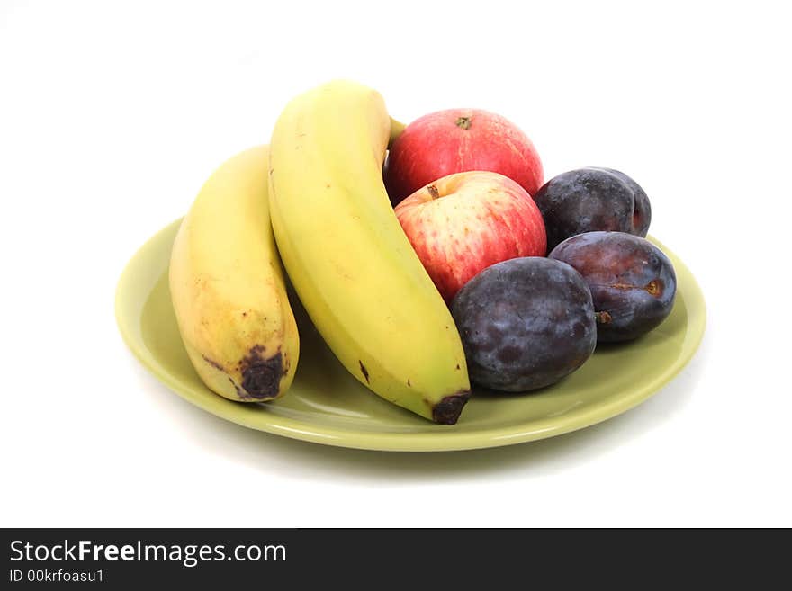 Fruits (banana, plums, apple) on the green plate