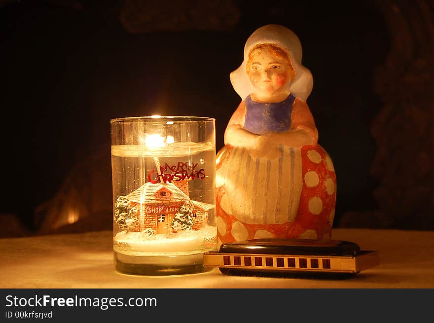 Composion with a candle, a harp and an ancient porcelain figure against the fireplace background. Composion with a candle, a harp and an ancient porcelain figure against the fireplace background.