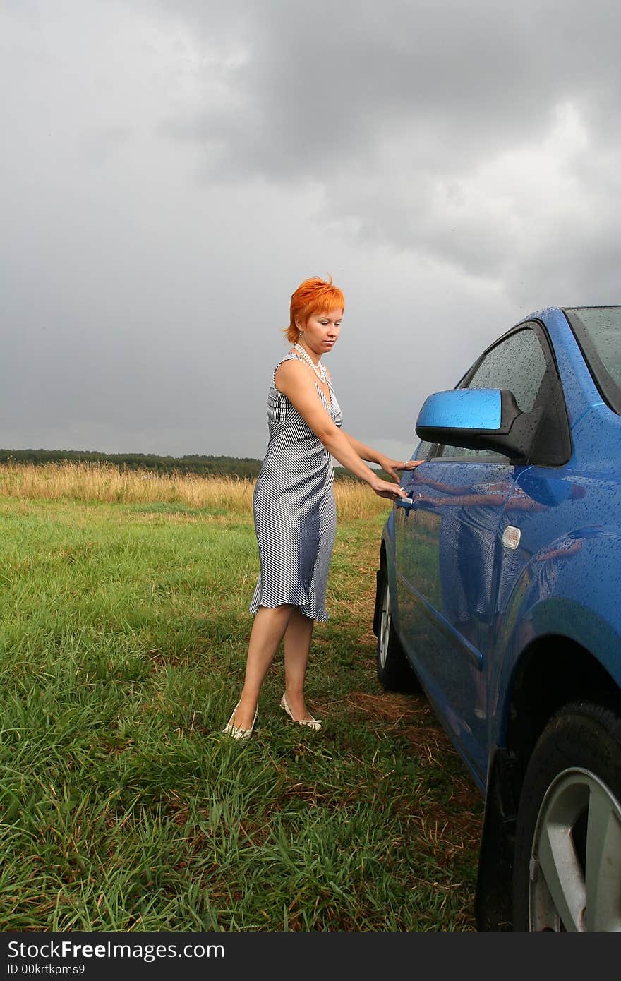 Red-haired woman in dress with blue car