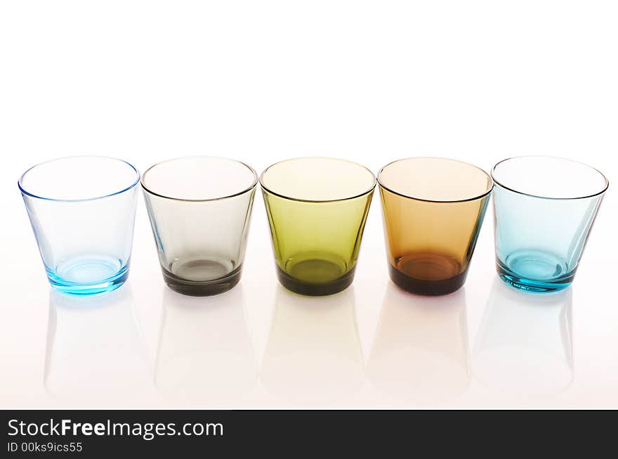 Colorful water glasses over a white reflective background