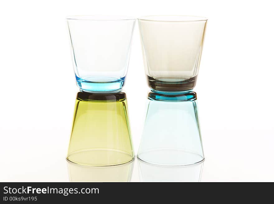 Colorful water glasses stacked over a white reflective background