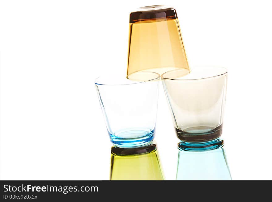 Colorful empty water glasses stacked over a white background