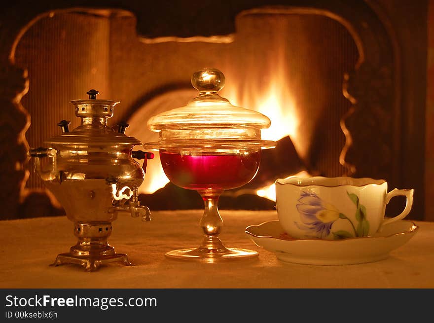 Russian style composition with a samovar, jam, and a cup if tea against the fire.