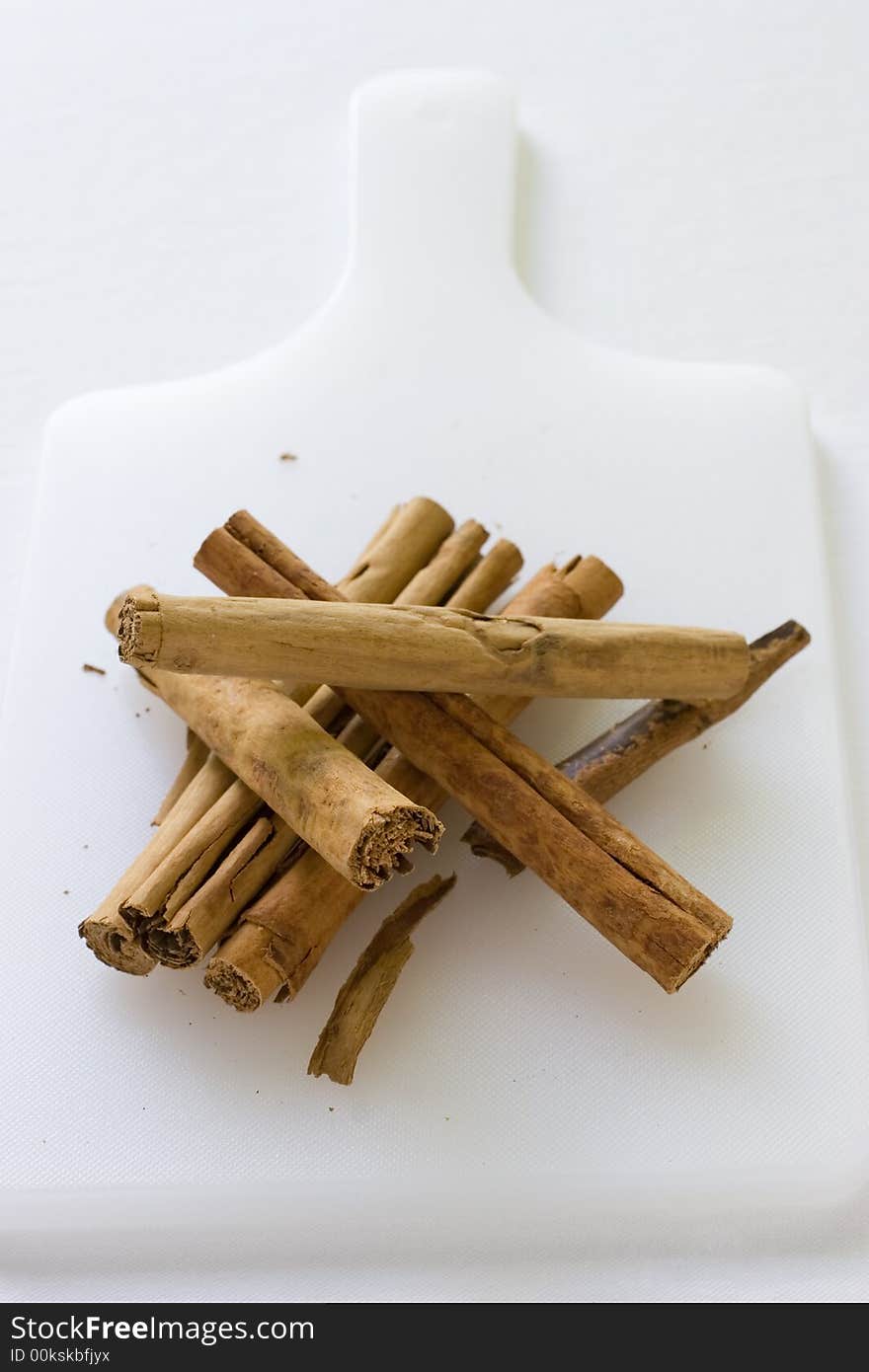 A arangement of Cinnamon Sticks on a white cutting board