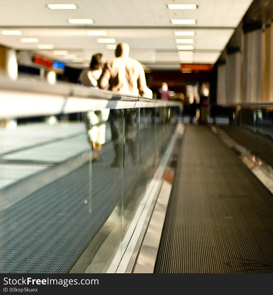 View from a movator at an airport of a couple slightly out of focus in the distance walking alongside