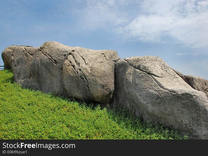 Cracked stones background with blue sky and front greegrass. Cracked stones background with blue sky and front greegrass