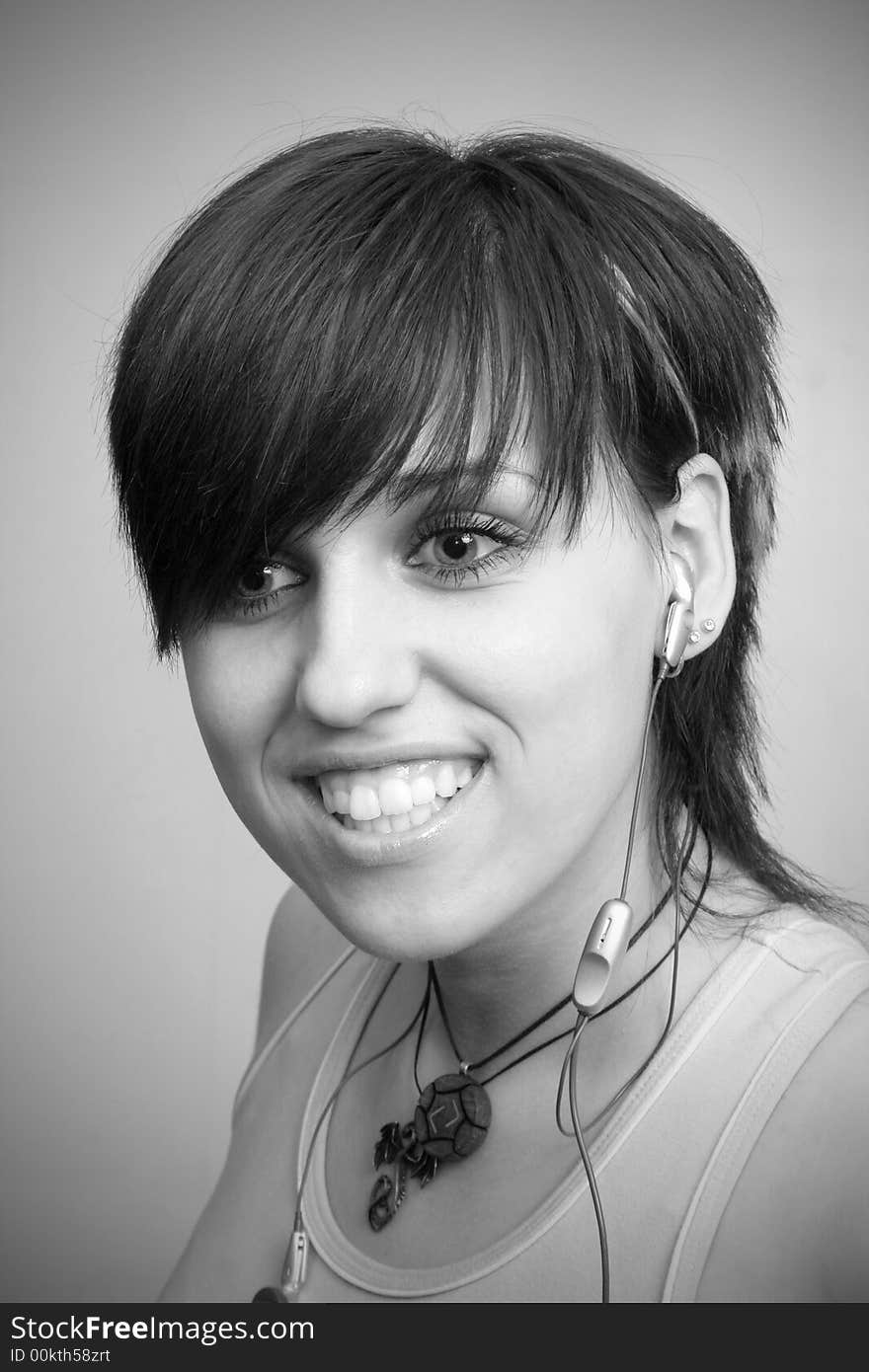 A smiling young girl with mobile's headphones, isolated on white