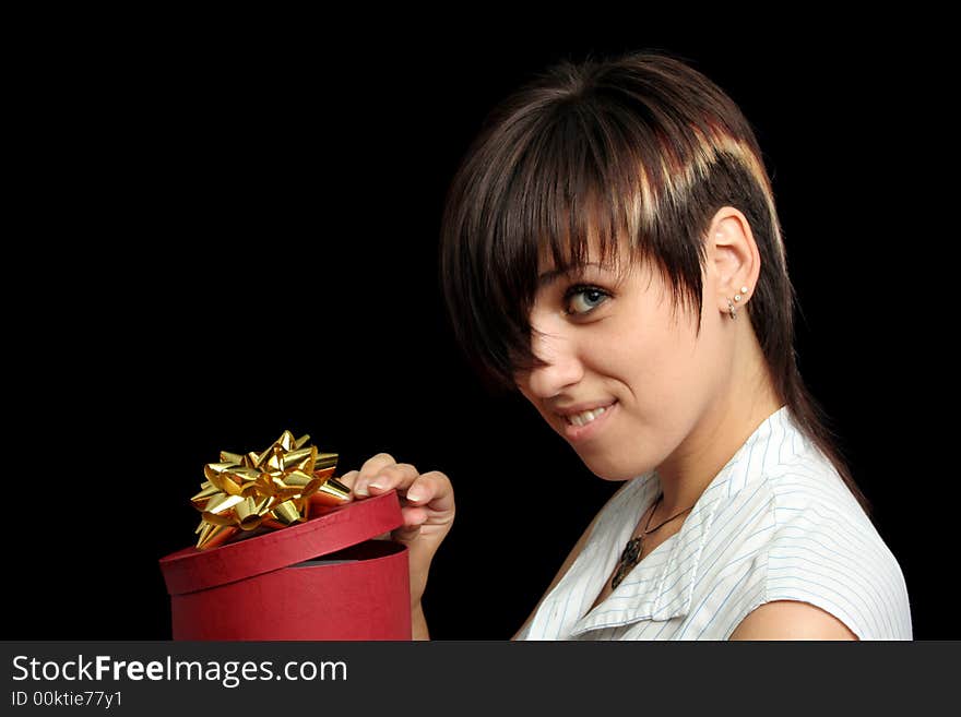 The young girl looks in a box with a gift, isolated on black background. The young girl looks in a box with a gift, isolated on black background