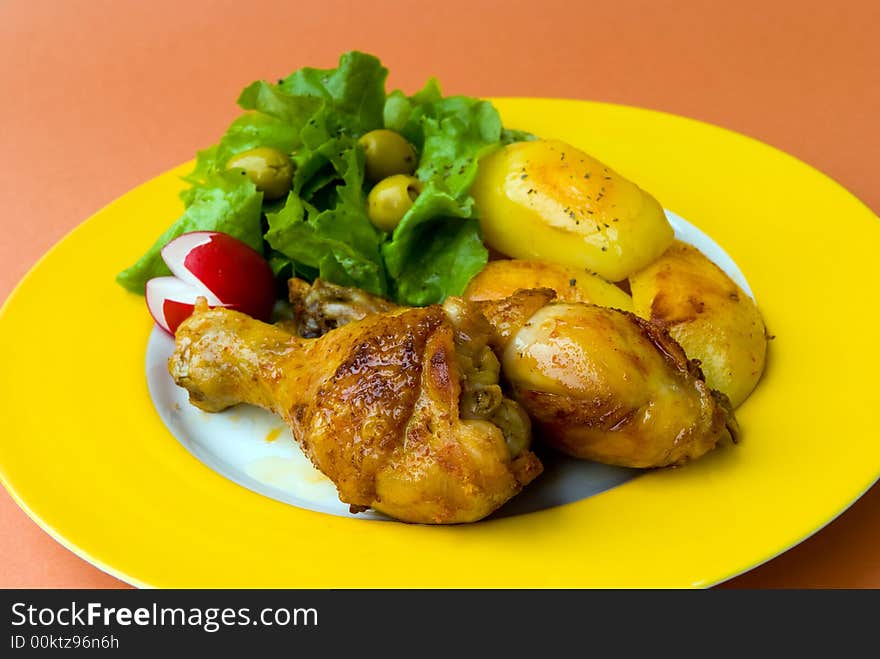 Roasted chicken legs with potatoes and salad.