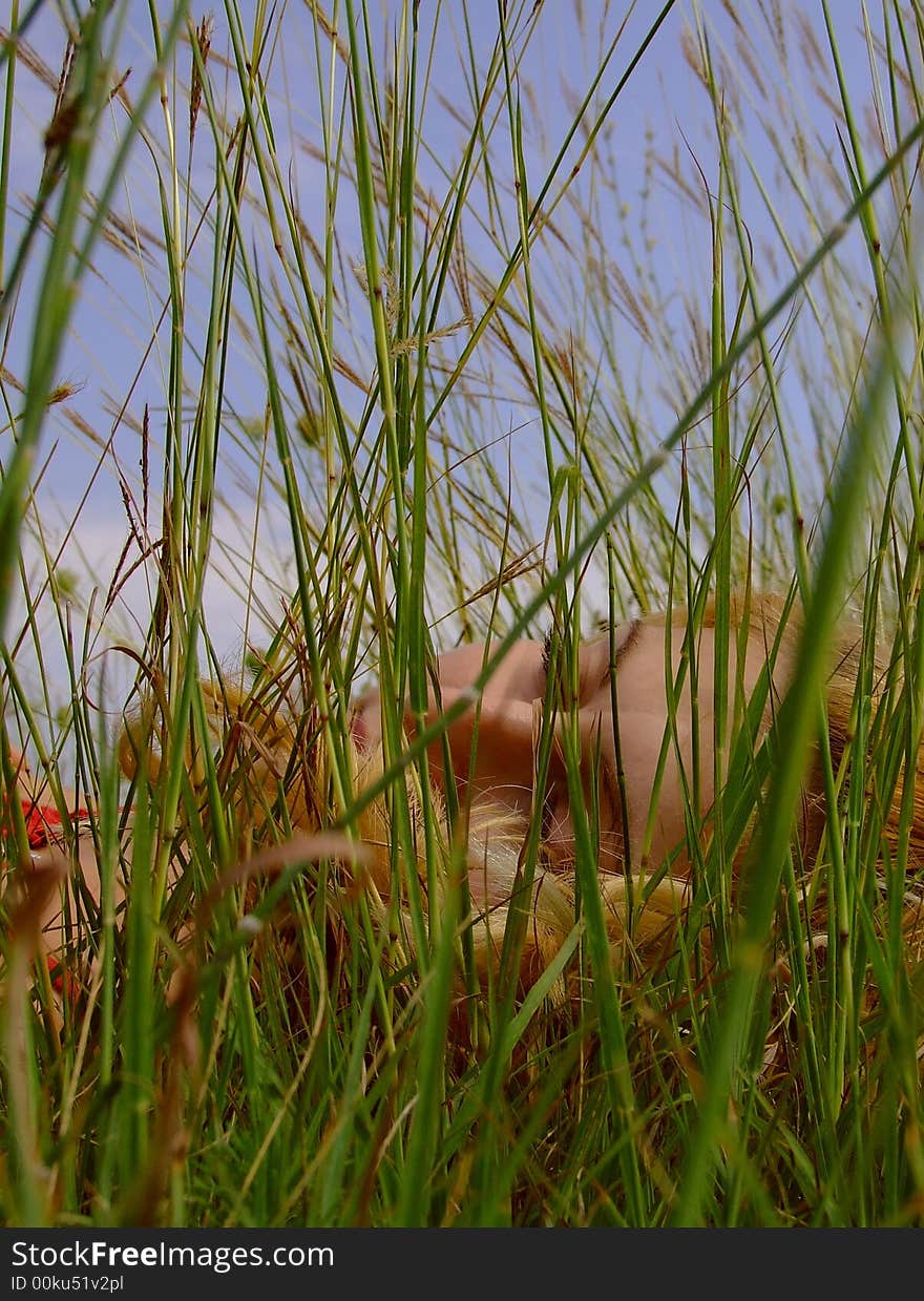 Young woman sleeping in the grass in a beautiful summer day.