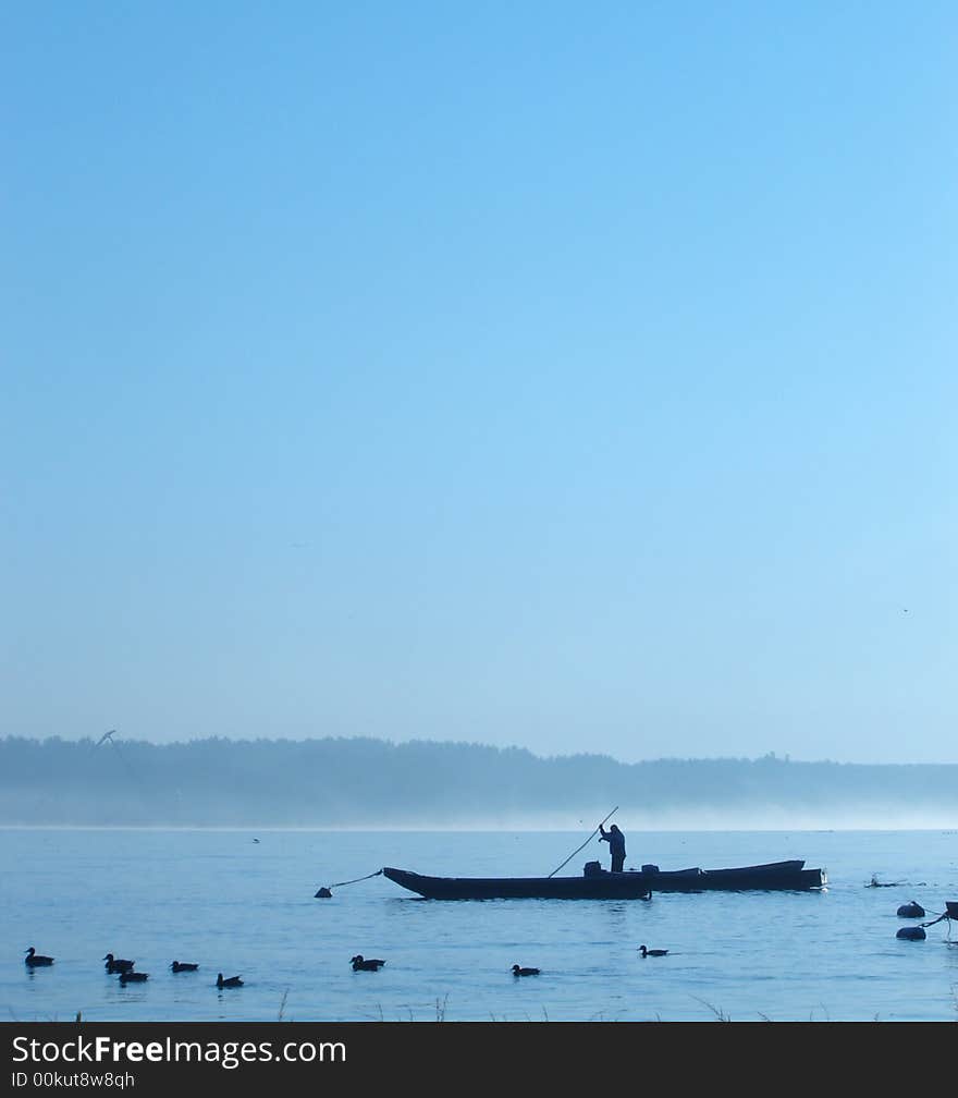 Fisherman in early morning. Ducks in foreground.