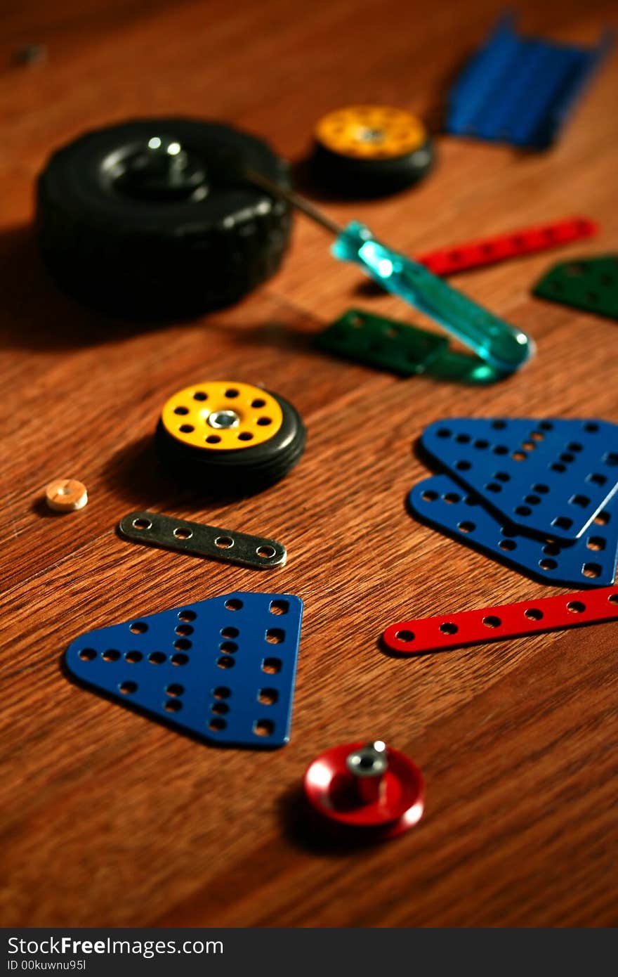 Colorful pieces of matal kit, metal sheets, wheels and a screwdriver - a toy for kids to assemble vehicles. Colorful pieces of matal kit, metal sheets, wheels and a screwdriver - a toy for kids to assemble vehicles.