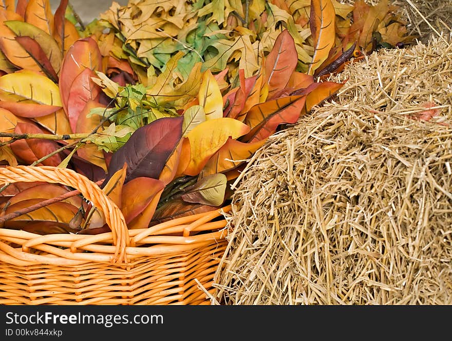 Autumn leaves and straw with a woven basket in warm colors for background. Autumn leaves and straw with a woven basket in warm colors for background.