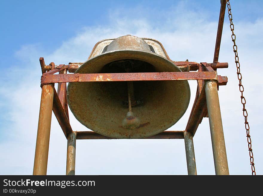 Antique, rusty bell in cemetery on poles with chain to ring it. Antique, rusty bell in cemetery on poles with chain to ring it