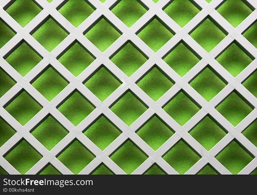 Image of a metal lattice over a green wall. Image of a metal lattice over a green wall