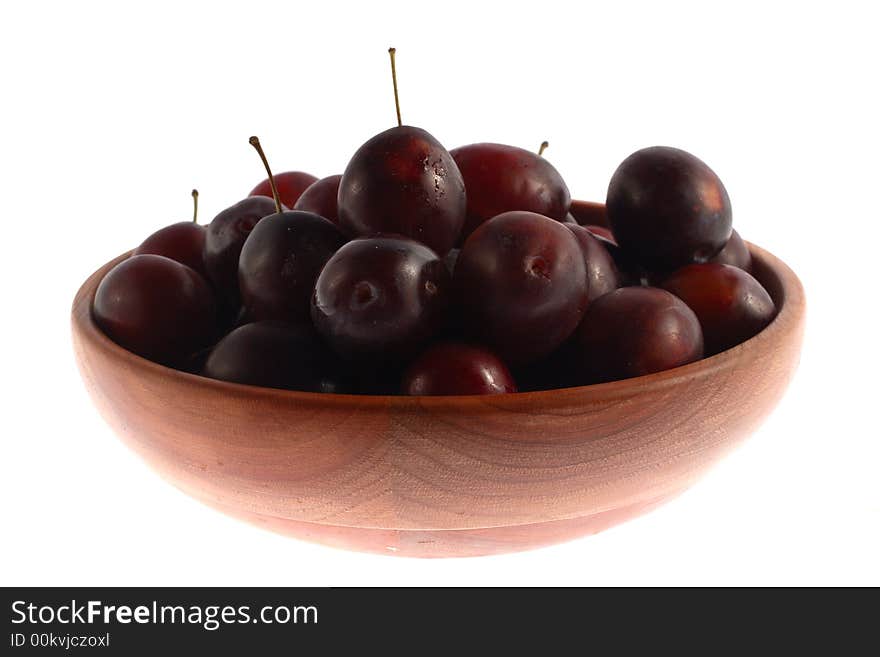 Plums in a big wood plate isolated. Plums in a big wood plate isolated