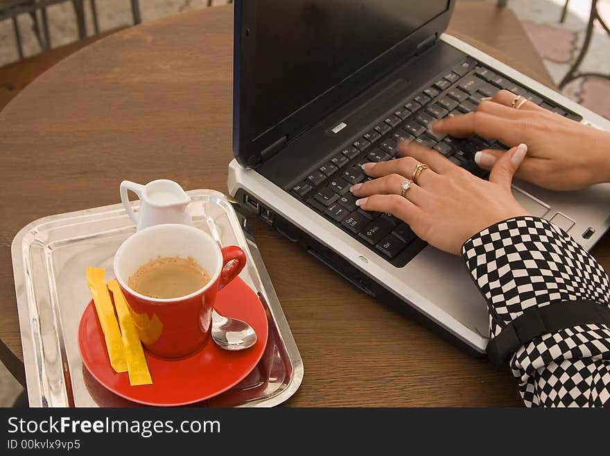 Detail image of woman hands typing on a laptop at a coffee table.Motion blur on fingers. Detail image of woman hands typing on a laptop at a coffee table.Motion blur on fingers.