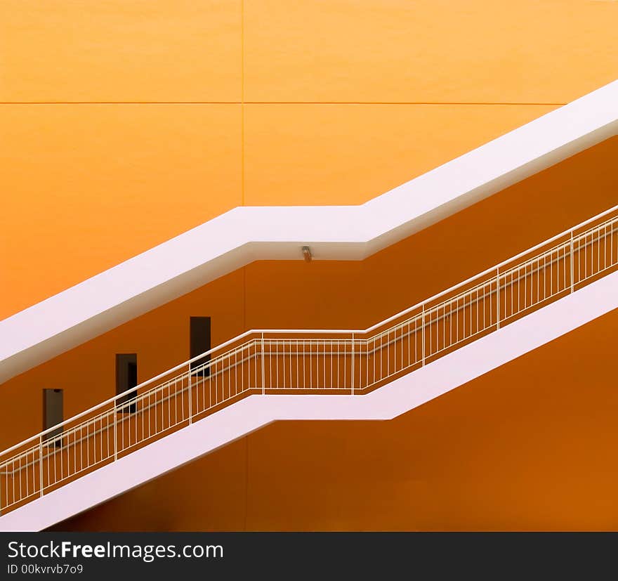 Staircase running diagonally up a freshly painted orange wall. Staircase running diagonally up a freshly painted orange wall.