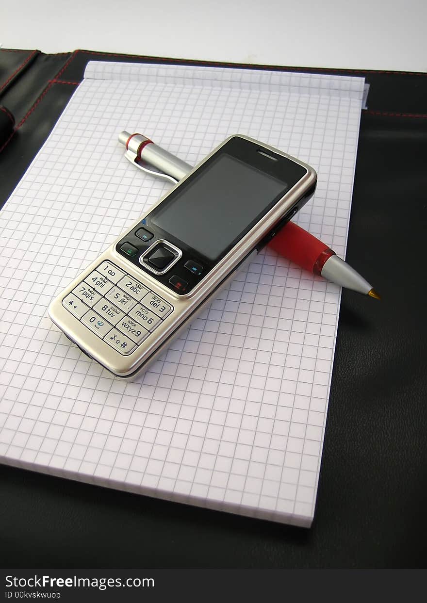 Mobile phone with pen are on business notepad. Mobile phone with pen are on business notepad.