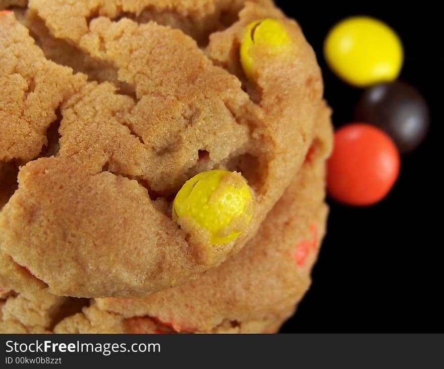 Close up photo of a stack of cookies with yellow, orange, and brown candy pieces.  Three pieces of the candy can be seen on the right side of the stack in the background. Close up photo of a stack of cookies with yellow, orange, and brown candy pieces.  Three pieces of the candy can be seen on the right side of the stack in the background.