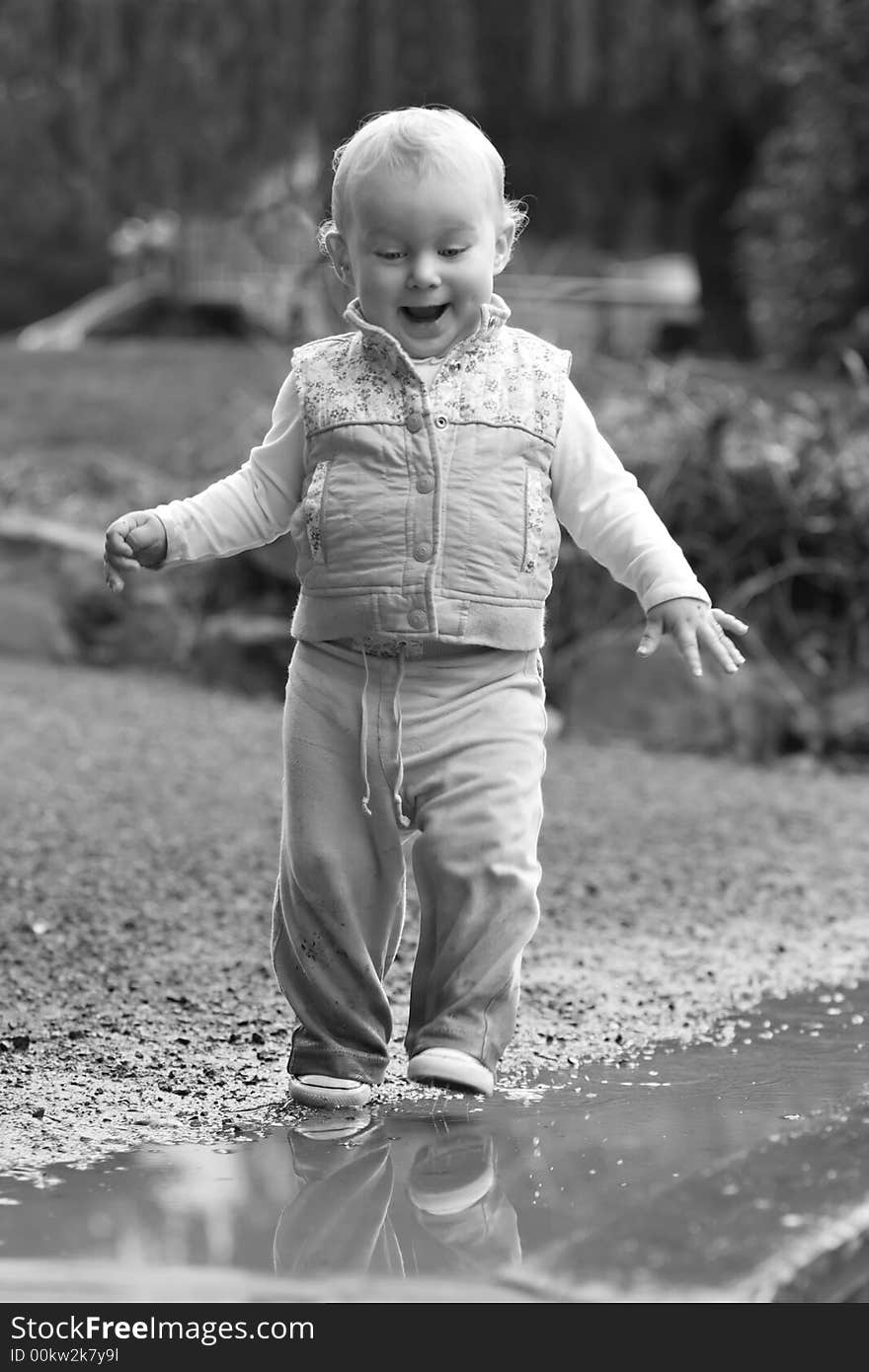 young happy smiling girl toddler stepping into mud puddle. young happy smiling girl toddler stepping into mud puddle