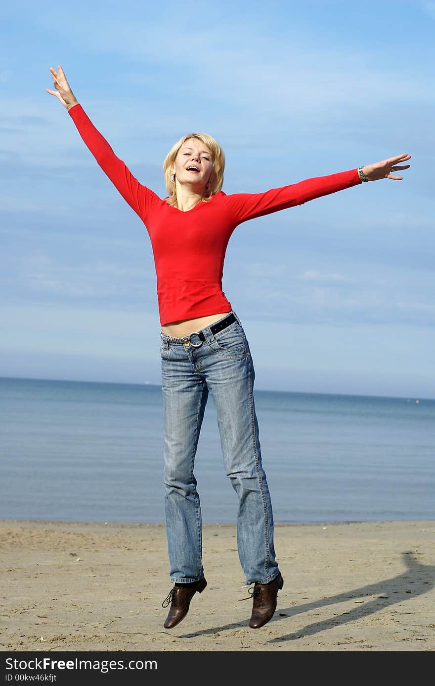 Jumping girl in red with sea on background