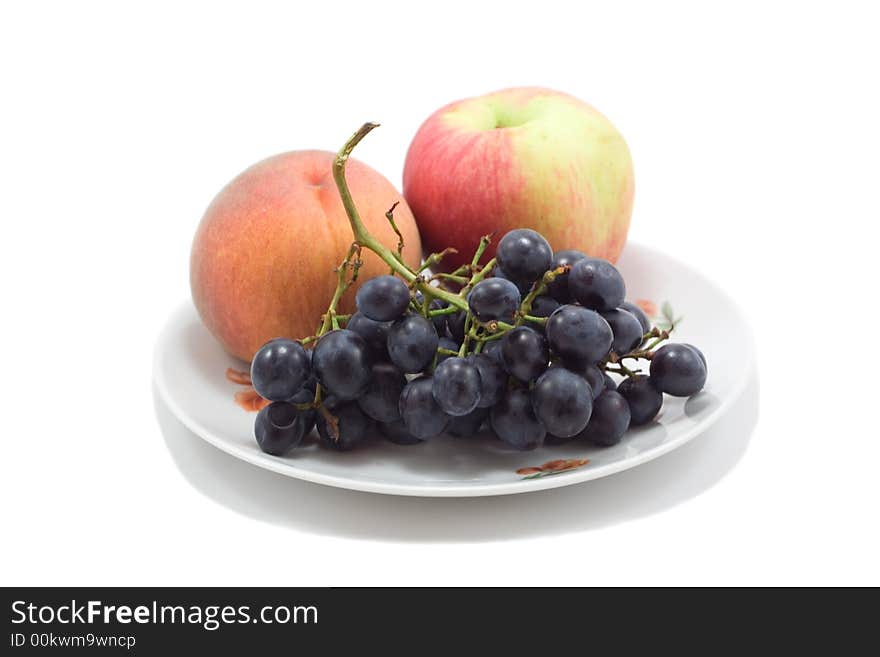 Plate with fruits, peach, apple and grapes, isolated on white