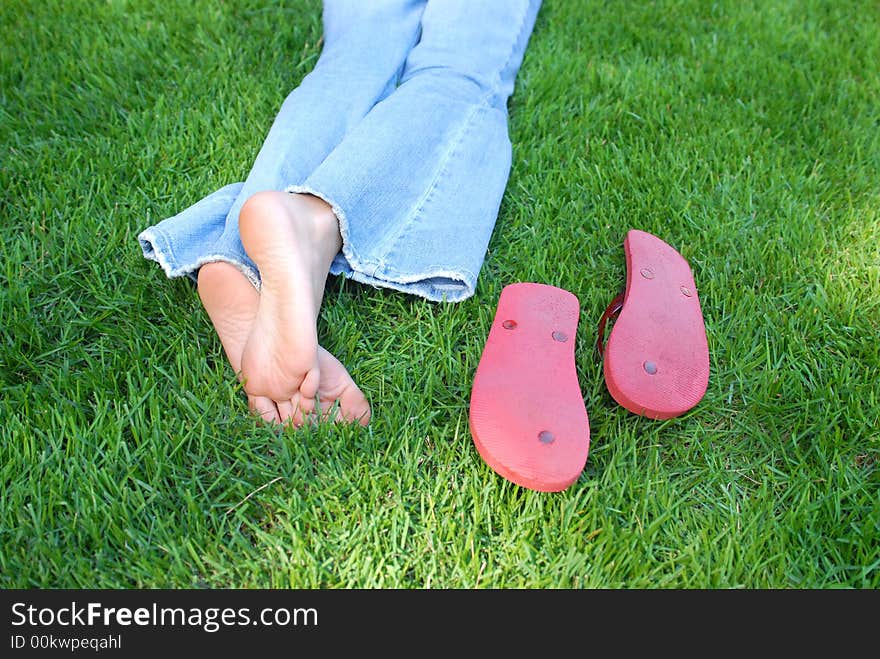 This is a picture of a girl relaxing in the yard in her bare feet on a cool summer day.