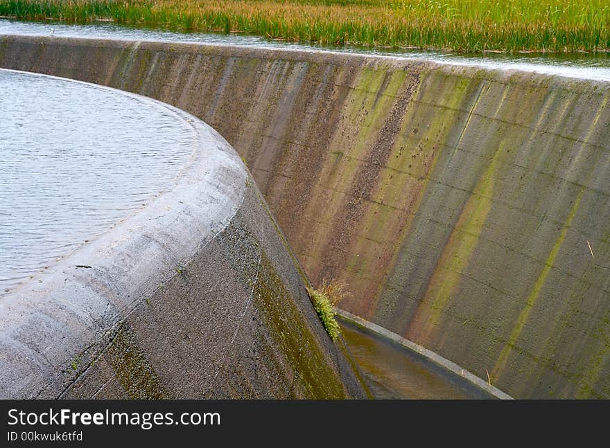 An overflowing dam with reeds. An overflowing dam with reeds