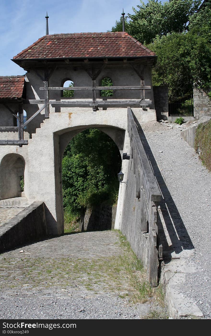 Part of an old wall with a red tile roof and a footbridge. Part of an old wall with a red tile roof and a footbridge.