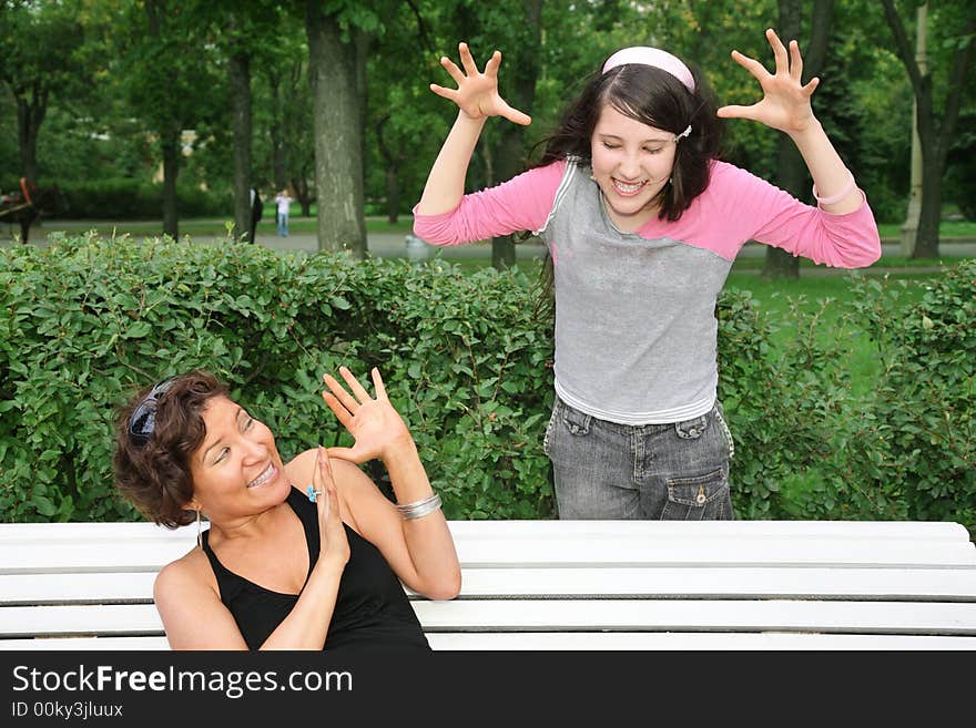 Mother sits on the bench, daughter stands near. Mother sits on the bench, daughter stands near