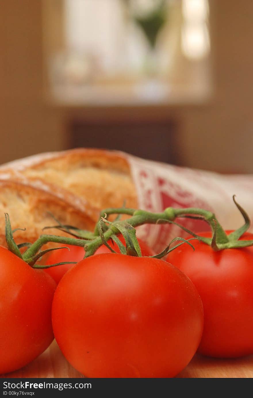 Upright of tomatoes and bread with sunny window behind. Upright of tomatoes and bread with sunny window behind