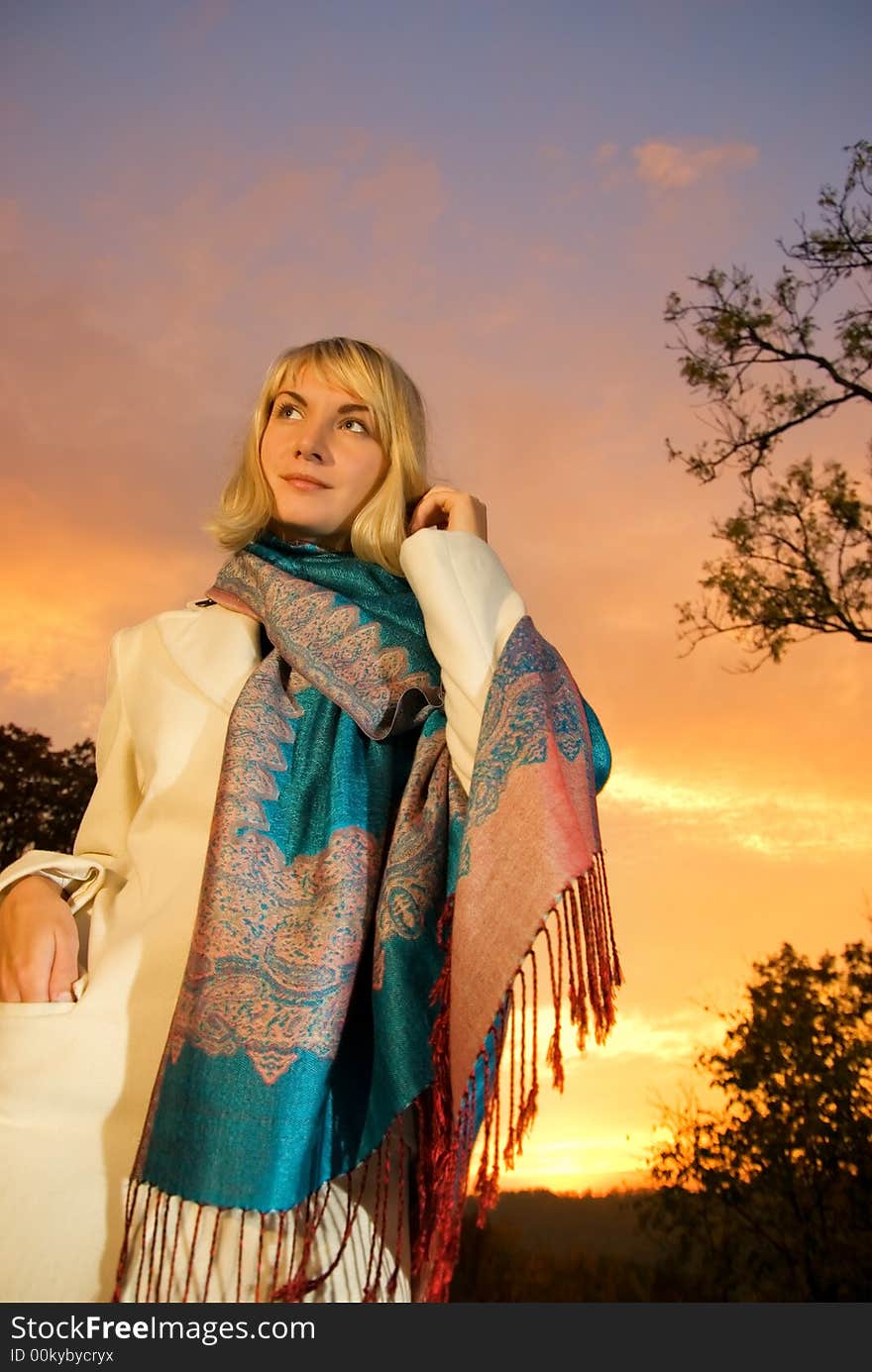 Blond girl on sunset sky background