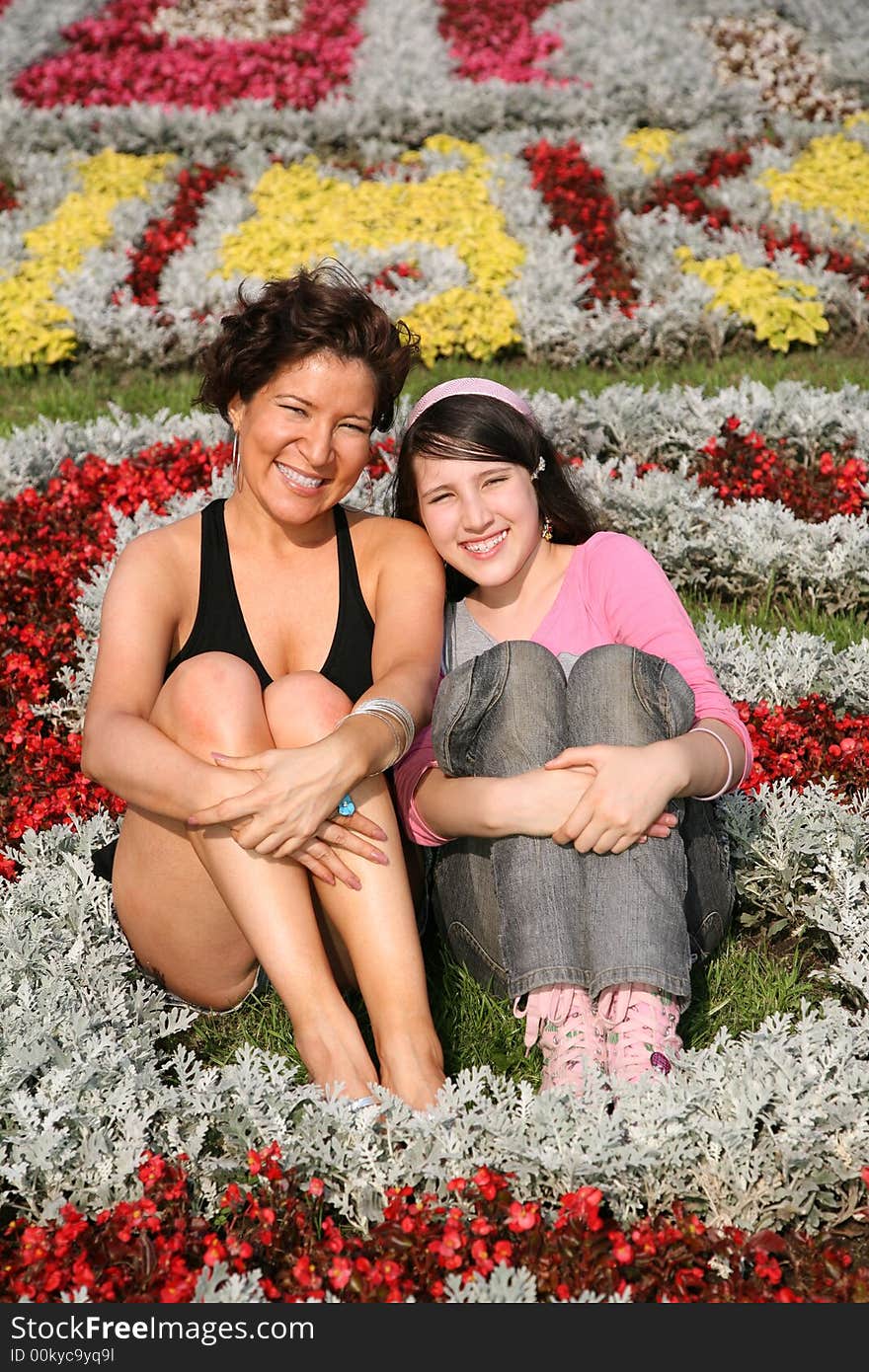 Mother and daughter sit among flowers