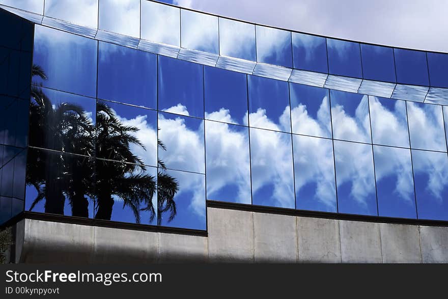 Palm trees, clouds, blue sky reflect and repeat in building window glass. Palm trees, clouds, blue sky reflect and repeat in building window glass