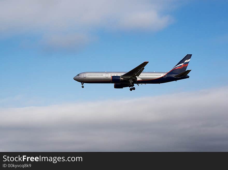 Airplane landing with blue sky and clouds in background