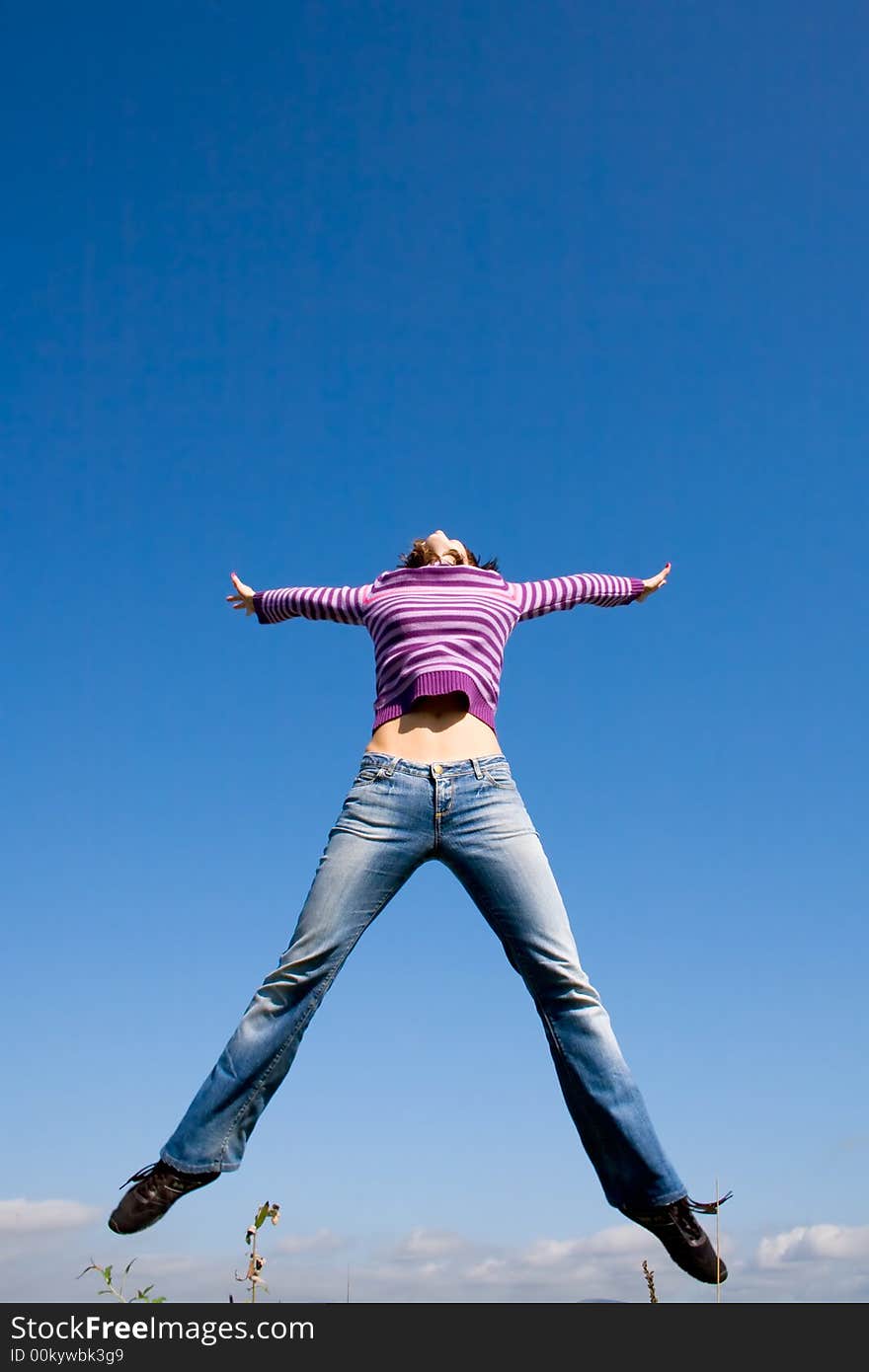 Girl jumping high, blue sky in background