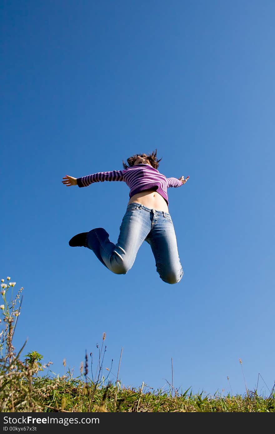 Girl jumping high, blue sky in background