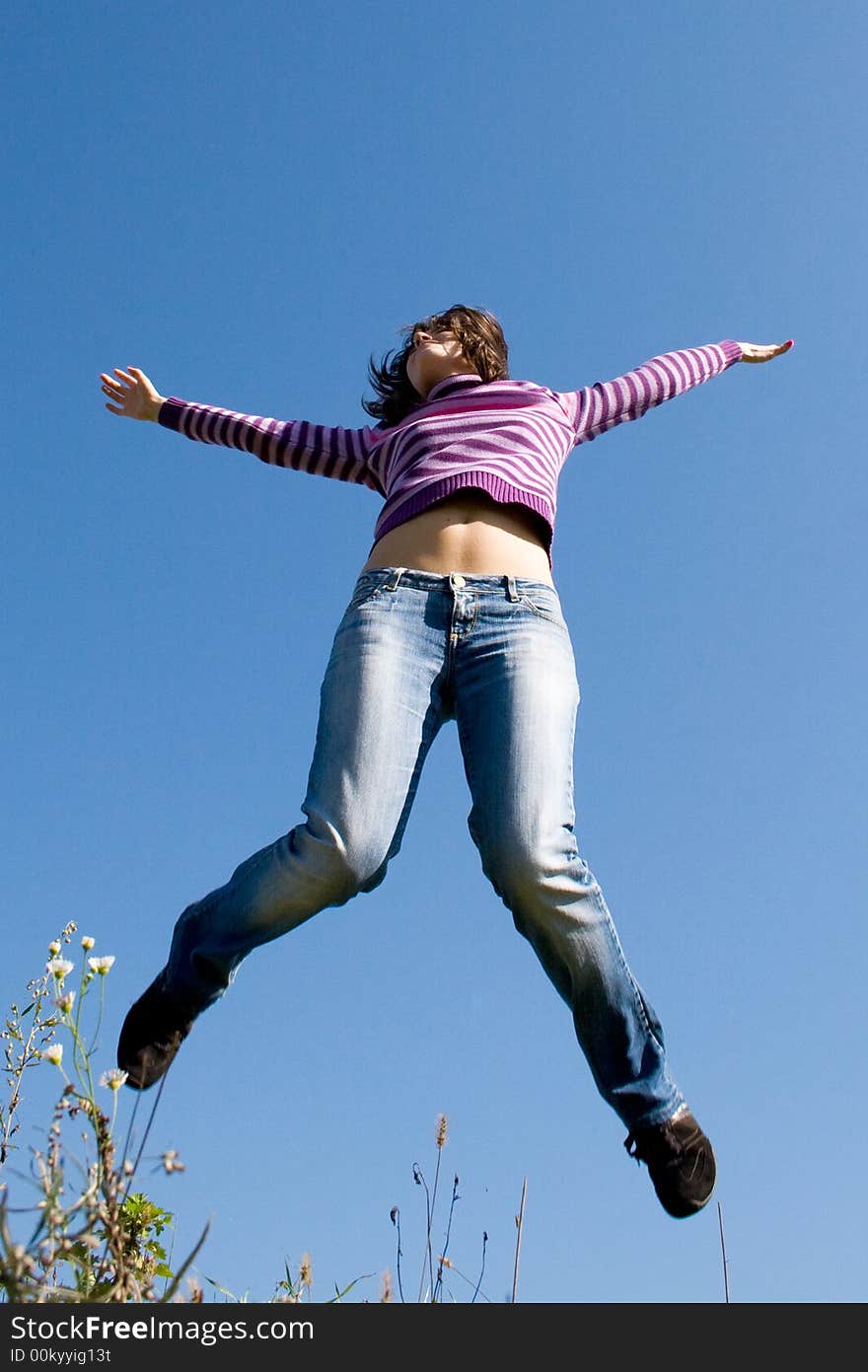 Girl jumping high, blue sky in background