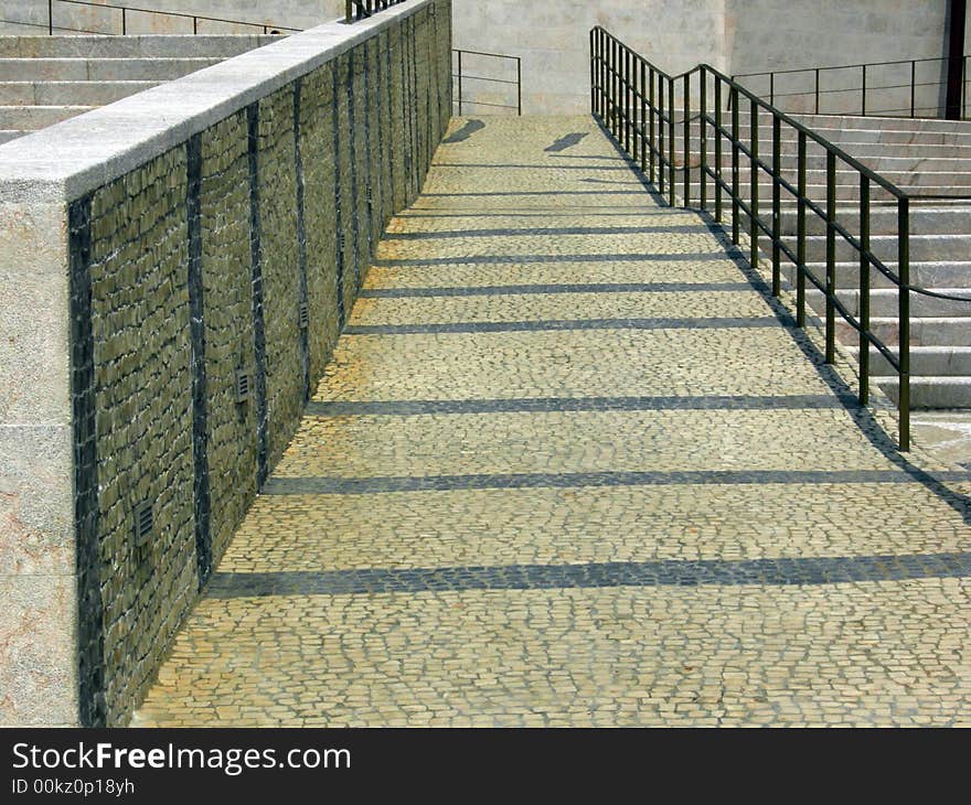 Portuguese sidewalk with white and black stones and a hand rail. Portuguese sidewalk with white and black stones and a hand rail