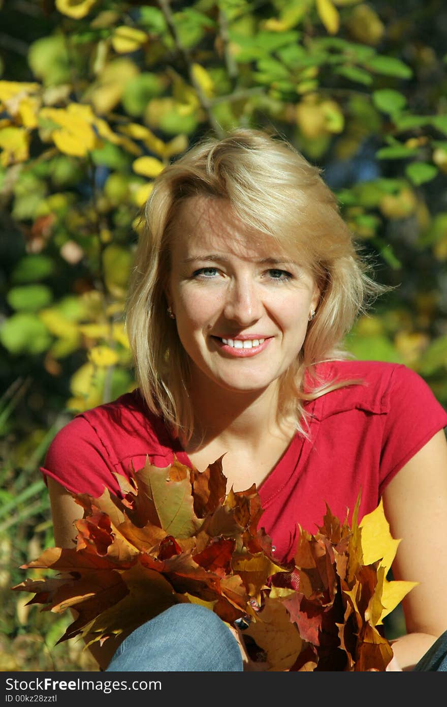 The beautiful girl with leaves of a maple